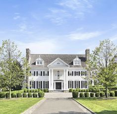 a large white house sitting on top of a lush green field