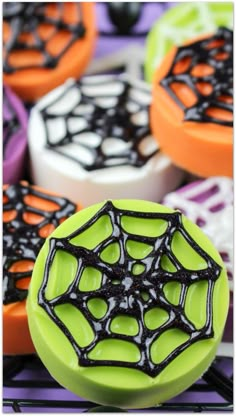 colorful cookies decorated with black icing and spider webs on top of each cookie