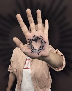 a person holding their hand up with a tattoo on it