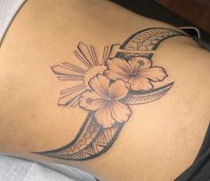 a woman's lower back tattoo with flowers and crescent moon on the left side