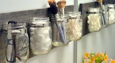 mason jars are lined up on the wall to hold makeup brushes and other personal care items