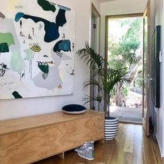 a living room filled with furniture and a large painting on the wall over a wooden table