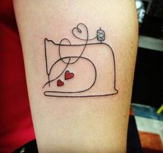 a tattoo on the arm of a woman with hearts and a sewing machine in it