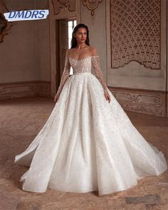 a woman in a white wedding dress with long sleeves and beading on the skirt