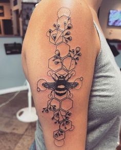 a woman with a tattoo on her arm that has a bee and flowers in it