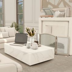 a living room with white furniture and a fireplace in the corner, as well as a laptop computer