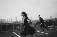 black and white photograph of two people running in a parking lot with buildings in the background