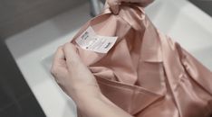 a woman is tying a pink satin ribbon on her necktie in front of a mirror