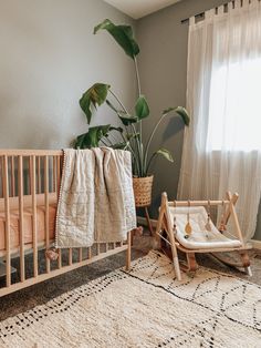 a baby's crib with a blanket on it next to a potted plant