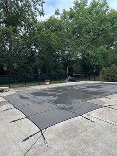 an empty tennis court surrounded by trees and fenced in area with no people on it