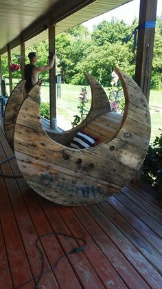 a man standing on top of a wooden moon shaped boat in the middle of a porch