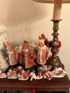 a wooden table topped with figurines next to a lamp and christmas decorations on top of it