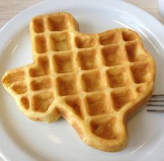 two waffles on a white plate with a fork