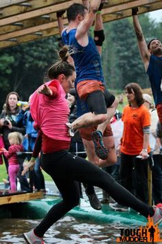 some people are jumping in the air on water skis and one is holding onto another person's leg