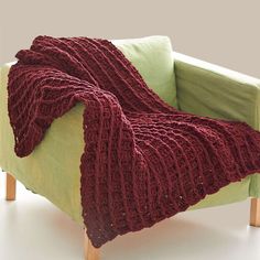 a green chair with a red knitted blanket on it