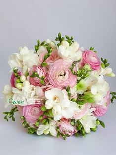 a bouquet of pink and white flowers with greenery on the top is sitting in front of a gray background