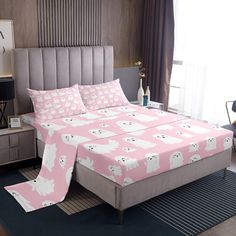 a bed with pink and white bedspreads in a bedroom next to a window