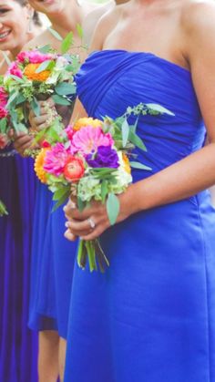 a group of women in blue dresses holding bouquets