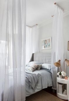 a white bedroom with sheer curtains and a bed