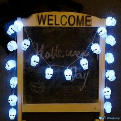 a welcome sign is decorated with skulls and lights in front of a blackboard that reads,'welcome halloween day '