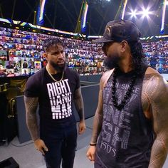 two men standing next to each other in front of a stadium full of people and fans