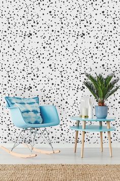 two chairs and a table in front of a wall with black dots on it