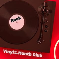 a vinyl record player sitting on top of a red table next to a black clock