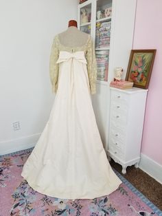 a wedding dress on display in front of a white cabinet and pink carpeted floor