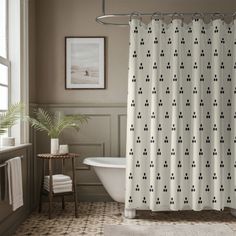 a white bath tub sitting next to a shower curtain in a bathroom on top of a tiled floor