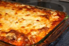 a casserole dish with meat, cheese and sauce in it on the stove