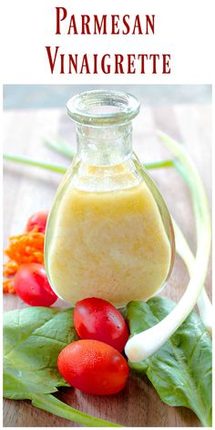 a bottle filled with dressing sitting on top of a wooden table next to tomatoes and lettuce