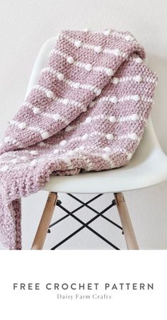 a pink and white blanket sitting on top of a chair next to a wooden table