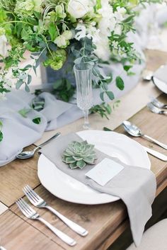 the table is set with white and green flowers, silverware, and napkins