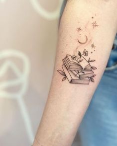 a person with a tattoo on their arm is holding a stack of books and stars