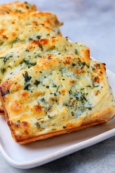 two pieces of bread with cheese and spinach on it sitting on a plate next to another piece of bread