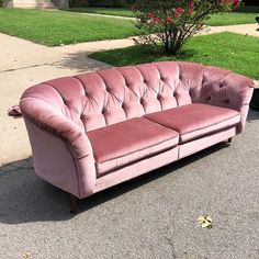 a pink couch sitting on top of a sidewalk