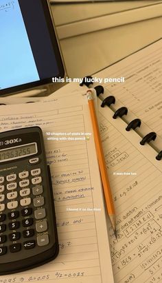 a calculator sitting on top of an open notebook next to a computer monitor