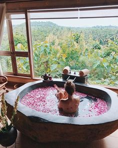 a woman sitting in a large stone bathtub with flowers on the floor next to it