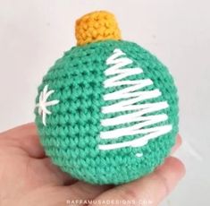 a crocheted christmas ornament in green and yellow with white writing on it