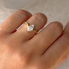 a woman's hand with a diamond ring on top of her left hand,