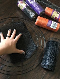 a person's hand on the top of a wire mesh basket next to rolls of toilet paper