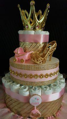 a three tiered cake decorated with gold and pink ribbon, shoes and tiara