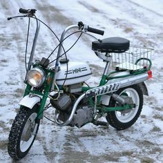 a small white and green motorcycle parked in the snow