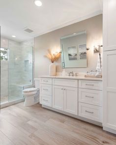 a large bathroom with white cabinets and wood floors