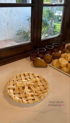 a pie sitting on top of a white counter next to some cups and bowls filled with food