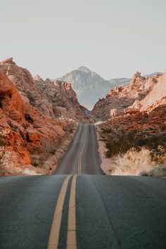 an empty road in the desert with mountains in the backgrounnd and no cars on it