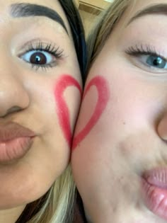 two women with painted hearts on their faces