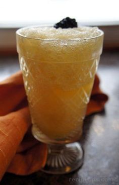 a glass filled with liquid sitting on top of a table next to an orange napkin