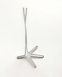 a metal object on a white surface that looks like a star ornament, with the letter k in it's center