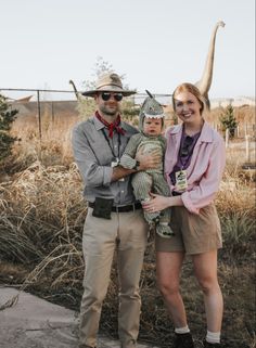 a man and woman standing next to each other holding a baby